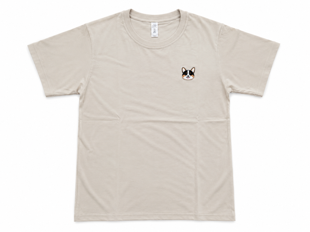 A light beige crewneck t-shirt with a small embroidered French Bulldog face on the left chest, displayed flat against a white background.